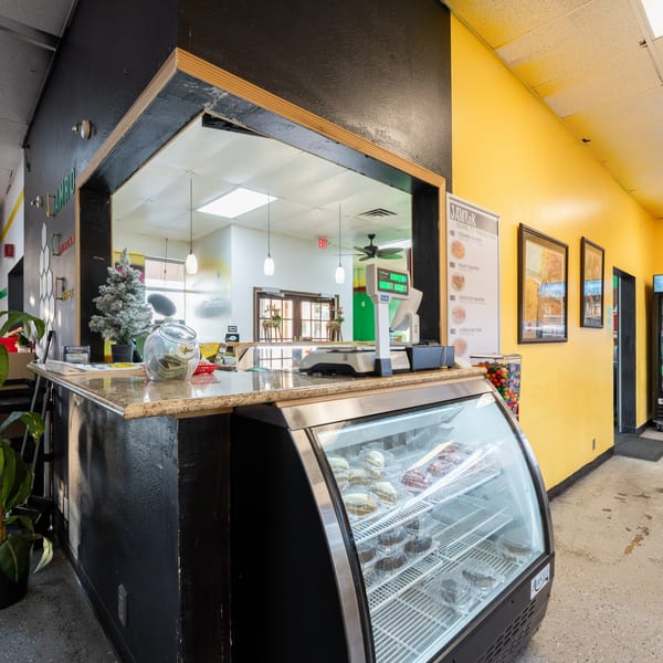 Interior view of JAMROK Caribbean Buffet's counter with a display case of pastries and a menu board.