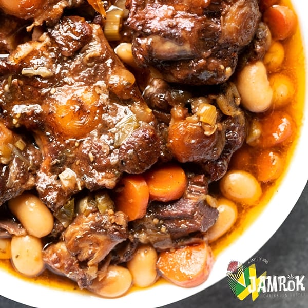 Close-up of Jamaican oxtail stew with butter beans and carrots in a rich brown sauce.