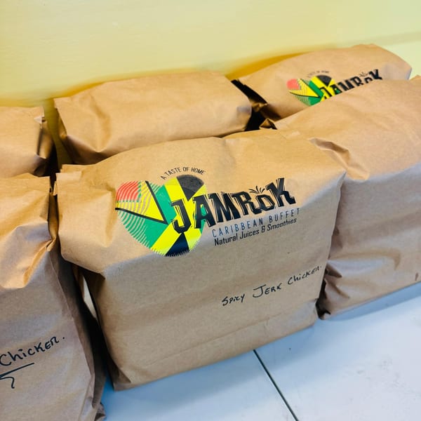 Several Jamrok Caribbean Buffet brown paper bags, one labeled "Spicy Jerk Chicken".