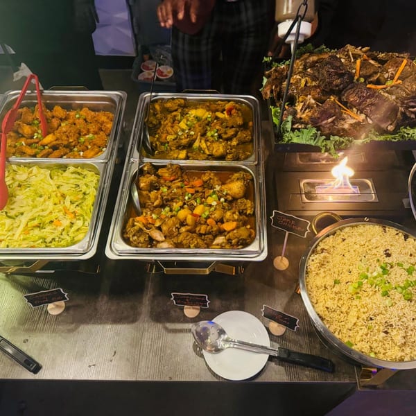 A Jamaican buffet spread with fried fish, curried chicken, cabbage, jerk chicken, and rice and peas.