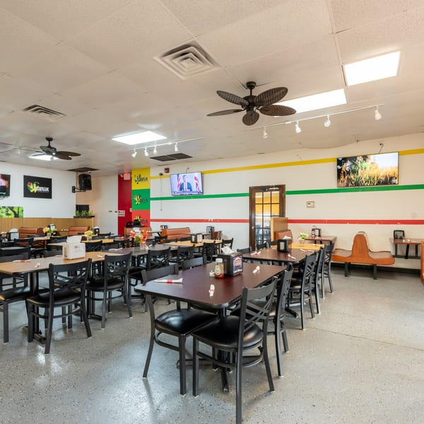 Interior of JAMROK CARIBBEAN BUFFET, showing dining tables, chairs, and Jamaican flag colors on walls.