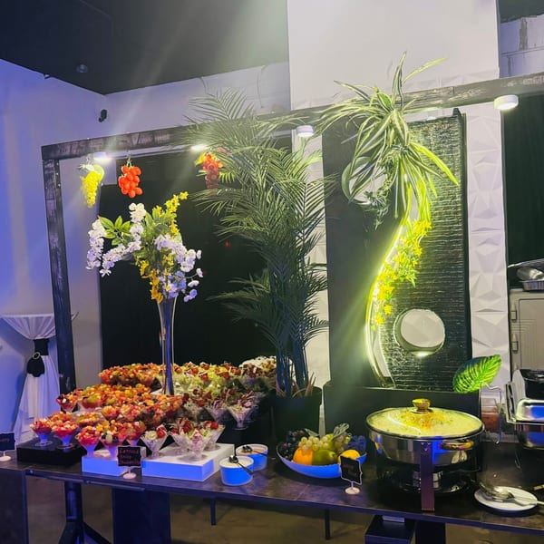 A buffet table at JAMROK CARIBBEAN BUFFET with fruit cups, salads, and a chafing dish.