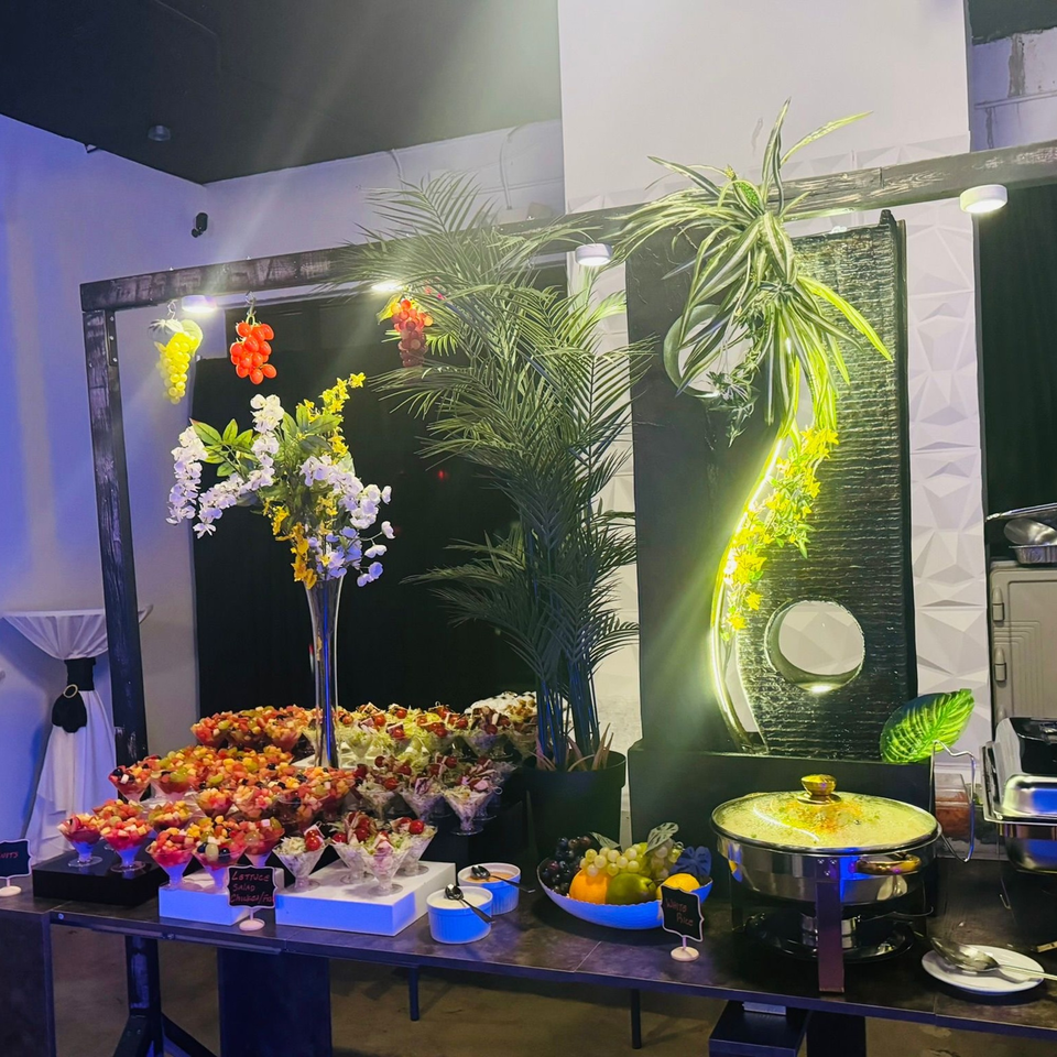 A buffet table at JAMROK CARIBBEAN BUFFET with fruit cups, salads, and a chafing dish.